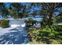 Charming home exterior showcasing a well-manicured lawn and large shade tree over the front yard at 271 Manor Rd, Venice, FL 34293