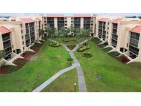 Condominium aerial view with verdant lawn, walking paths, palm trees, and lovely landscaping at 3006 Caring Way # 304, Port Charlotte, FL 33952