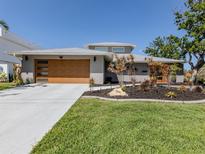 Modern home showcasing a wooden garage door and vibrant landscaping at 616 Gardenia Dr, Venice, FL 34285
