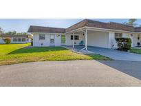 Cozy home with white exterior, front yard, and covered parking spot with blue chair at 680 Circlewood Dr # W3, Venice, FL 34293