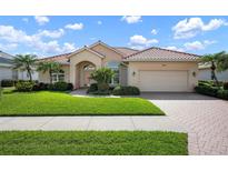 Charming single-story home featuring a red tile roof, paver driveway, and lush green landscaping at 744 Fringed Orchid Trl, Venice, FL 34293