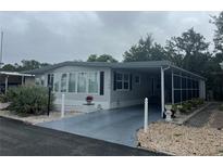 Charming mobile home featuring neutral tones, a screened porch, and a carport with decorative landscaping at 795 Cervina N Dr, Venice, FL 34285