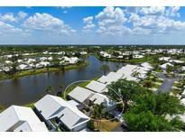 An aerial view of a lakeside home with white roof, lush landscaping, and serene water views at 799 Harrington Lake N Dr # 73, Venice, FL 34293