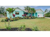 Charming single-story home with colorful landscaping, palm trees, and an attached two-car garage at 990 Sea Fox Rd, Venice, FL 34293