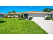 Well-maintained home featuring a lush green lawn, beautiful landscaping, and an attached two-car garage at 1004 Deer Run, Venice, FL 34293