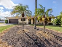 Charming single story home featuring mature palms, a two-car garage and a covered front porch at 1101 Southland Rd, Venice, FL 34293
