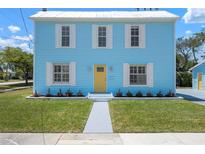 Charming two-story home with a light blue exterior, white trim, yellow door, and well-manicured lawn at 121 Dolly St, Punta Gorda, FL 33950