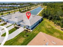 Stunning aerial view of a modern townhome with a paver driveway, lush landscaping, and a serene waterfront view at 12418 Asana Ct, Venice, FL 34293