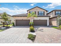 Inviting home featuring a neatly manicured lawn, paver driveway and a two-car garage at 12500 Ghiberti Cir # 101, Venice, FL 34293
