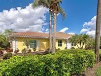 Charming single-story home with a tile roof, manicured landscaping, and beautiful palm trees at 13150 Huerta St, Venice, FL 34293