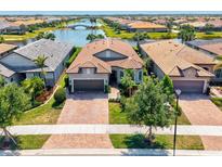 Stunning aerial view of home with beautiful landscaping, lake view and brick driveway at 13511 Esposito St, Venice, FL 34293