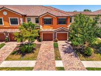 Charming two-story townhome featuring a clay tile roof, brick driveway, and attached two-car garage at 20237 Lagente Cir, Venice, FL 34293