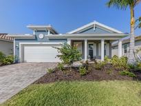 Inviting single-story home features a well-manicured lawn, brick driveway, and attached two-car garage at 20285 Symphony Pl, Venice, FL 34293