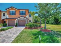 Charming townhome with brick paver driveway, two-car garage, and lush landscaping at 20290 Lagente Cir, Venice, FL 34293