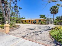 Charming single-story home with a circular driveway surrounded by lush, tropical landscaping at 337 Harbor S Dr, Venice, FL 34285