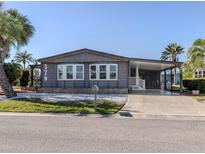 Charming home featuring well-maintained landscaping, a covered carport and gray siding for a polished look at 379 Harbor Isles Dr, North Port, FL 34287