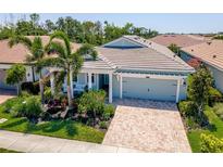 Charming single-Gathering home featuring a brick driveway, two-car garage, and tropical landscaping at 5632 Long Shore Loop, Sarasota, FL 34238