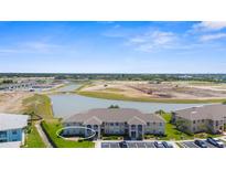 Expansive aerial view of a modern condo community with a picturesque lake and manicured green spaces at 5800 Sabal Trace Dr # 101, North Port, FL 34287