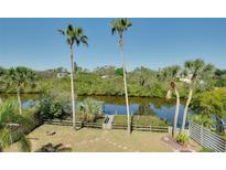 A backyard view with a waterway, a private dock, palm trees, lush greenery, and a fire pit at 610 Alligator Dr, Venice, FL 34293
