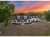Stunning exterior of this two-story home featuring a lush, landscaped lawn and inviting covered porch at sunset at 6824 283Rd E St, Myakka City, FL 34251