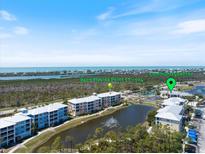 Aerial view of a condo community with waterfront views, a lake with a fountain, and well-maintained landscaping at 8403 Placida Rd # 304, Placida, FL 33946