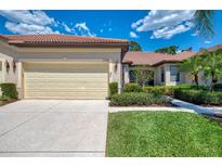 Home exterior featuring a tan two-car garage, driveway, and well-maintained landscaping at 11186 Batello Dr, Venice, FL 34292