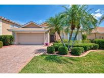 Charming single-story home with a brick driveway, lush landscaping, and a two-car garage at 11437 Dancing River Dr, Venice, FL 34292