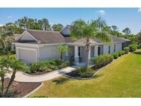 Charming single-story home with a well-manicured lawn, lush landscaping, and a welcoming covered porch at 11455 Fort Lauderdale Pl, Venice, FL 34293