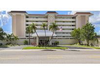 Elegant multi-story condo building featuring well-manicured landscaping and a charming entrance area with an American flag at 1150 Tarpon Center Dr # 3G 307, Venice, FL 34285