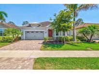 Charming home with a brick driveway, mature landscaping, and a lovely red front door at 11711 Alessandro Ln, Venice, FL 34293