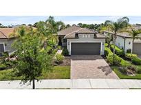 Charming single-story home showcasing a tile roof, two-car garage, brick paver driveway, and well-maintained landscaping at 12897 Oriago St, Venice, FL 34293