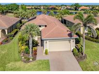 Beautiful home featuring a well-manicured lawn, tile roof, and a two-car garage, close to a scenic lake at 162 Palazzo Ct, North Venice, FL 34275