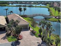 Beautiful lakefront property with a bridge, lush landscaping, and a paver driveway at 19240 Isadora St, Venice, FL 34293