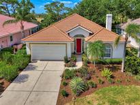Charming single-story home with a red front door, barrel tile roof and lush landscaping at 2318 Harrier Way, Nokomis, FL 34275