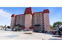 Spacious condo building with a light exterior, parking, and palm trees against a blue sky at 244 Saint Augustine # 605, Venice, FL 34285