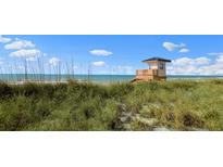 Beautiful beach with a lifeguard tower surrounded by dune grass under a blue sky at 400 Base # 225, Venice, FL 34293