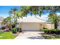 Charming yellow home featuring a two-car garage and a well-maintained lawn with lush landscaping at 542 Clubside Cir # 20, Venice, FL 34293