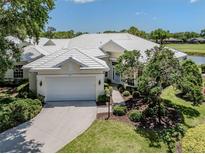 Well-maintained home featuring a two-car garage, mature landscaping, and a white tile roof at 553 Fallbrook Dr, Venice, FL 34292