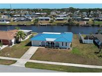 Waterfront home featuring a vibrant blue roof, well manicured lawn, and canal views at 6422 Otis Rd, North Port, FL 34287