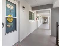 Exterior condo hallway with unit 106 featuring a white door, welcome decoration, and a covered walkway at 649 Tamiami S Trl # 106, Venice, FL 34285