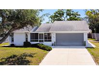Charming single-story home with a gray roof, a 2-car garage, a cozy front porch, and well-maintained landscaping at 985 Everest Rd, Venice, FL 34293