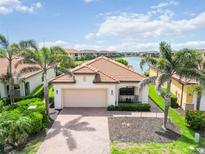 Charming single-story home features a tile roof, brick driveway, two-car garage, and lush landscaping at 10093 Cozy Grove Dr, Venice, FL 34293