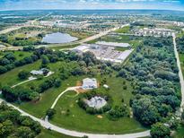 Expansive aerial view of a beautiful estate featuring lush landscaping, a private pond, pool, and neighboring commercial area at 1104 Twin Laurel Blvd, Nokomis, FL 34275