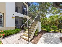 Inviting two-story condo with private entrance, featuring landscaped grounds and elegant iron railing on the stairway at 129 Preserve Pl # D, Nokomis, FL 34275