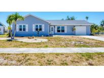 Charming single-story home featuring a light blue exterior and well-maintained front yard, perfect for curb appeal at 13579 Romford Ave, Port Charlotte, FL 33981