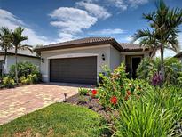 Charming home featuring a two-car garage, lush landscaping and a brick driveway at 13731 Vadini St, Venice, FL 34293