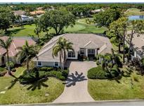 Stunning home with lush landscaping, palm trees, and a brick driveway leading to a golf course view at 2022 Calusa Lakes Blvd, Nokomis, FL 34275