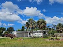Charming home with palm trees and a hammock, set against a bright blue, partly cloudy sky at 205 Jessica N St, Nokomis, FL 34275