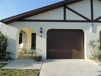 Charming front exterior showcasing a well-maintained lawn, arched entry, and a two-car garage at 211 High Point Dr # 211B, Englewood, FL 34223