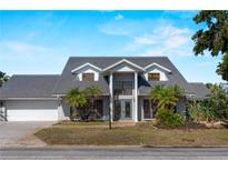 Stately two-story home with a gray roof, manicured landscaping and a brick driveway, offering timeless curb appeal at 318 Oakwood Cir, Englewood, FL 34223